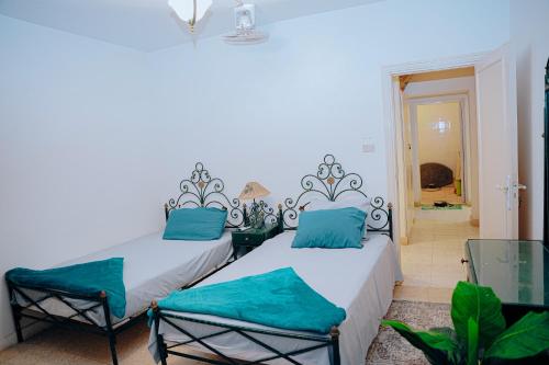Qaryat at Ta‘mīr as Siyāḩīyah4 bedrooms villa with private pool in Tunis village faiuym的白色客房的两张床,配有蓝色枕头
