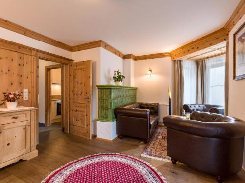 迈尔霍芬亚斯多霍夫小屋的客厅配有皮革家具和绿色壁炉