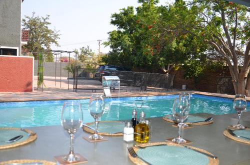 温特和克Windhoek Gardens Boutique Hotel的游泳池前带酒杯的桌子