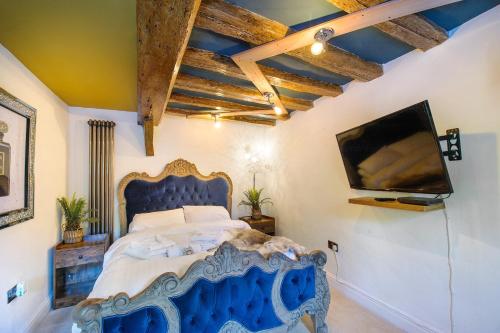 萨弗伦沃尔登King Suite In 600 Year Old Manor House In Saffron Walden North Essex的一间卧室配有蓝色的床和一台平面电视
