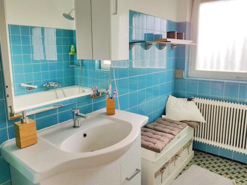 FußachHaus am Bodensee的蓝色瓷砖浴室设有水槽和浴缸