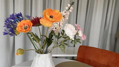 梅珀尔bij DE RODE DEUR的白色的花瓶,上面摆放着五颜六色的花朵