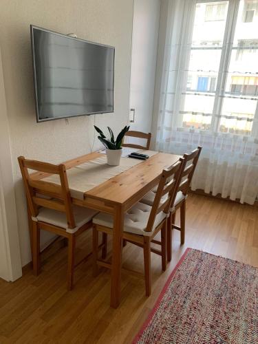 温特图尔2 Zimmer Appartement的一张木桌,配有两把椅子和墙上的一台电视