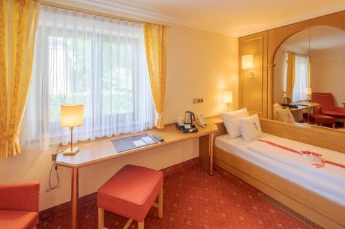 上施莱斯海姆祖姆选帝侯城堡公园酒店的配有一张床、一张书桌和一扇窗户的酒店客房
