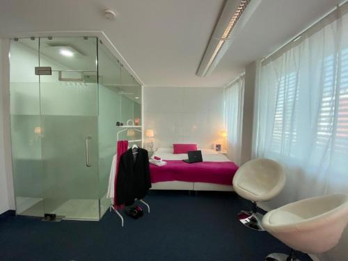 威斯巴登Business Hotel Wiesbaden PRIME的浴室设有粉红色的床和玻璃淋浴间。
