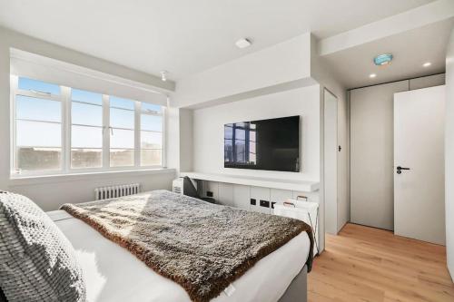 伦敦Luxury Kensington Flat with Terrace and AC的一间卧室配有一张床和一台平面电视