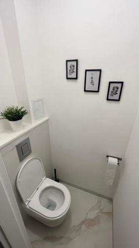 华沙Warszawa Krucza Pokoje的浴室设有卫生间,墙上有3幅图片