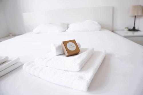 卢森堡Lovely Modern 1 BR apartment的床上的毛巾堆上的一个钟