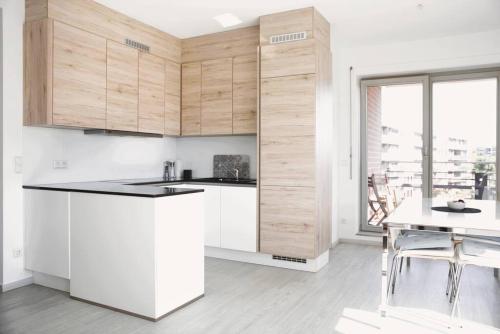 卢森堡Lovely Modern 1 BR apartment的厨房配有白色橱柜、桌子和窗户。