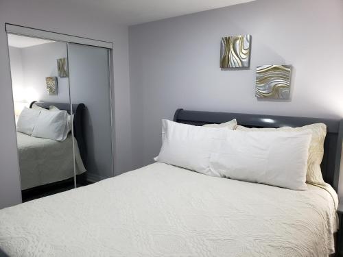 布兰普顿Luxurious 1BR-1BA Apartment Bright Spacious with free parking的一间卧室配有一张带白色枕头和镜子的床
