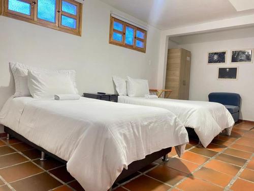 波哥大Zana Hotel Boutique的一间卧室配有两张床、白色床单和窗户。