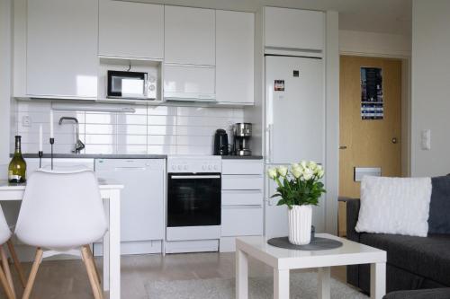 奥卢Lovely 2R apartment的厨房配有白色橱柜和花瓶桌子