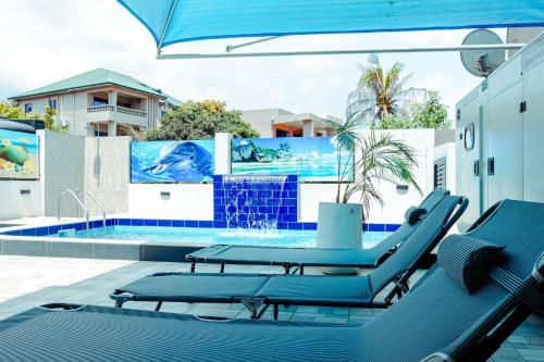 阿克拉Richie's Appartments的一个带蓝色躺椅和遮阳伞的游泳池