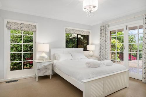 黑荒地林伍德度假屋的白色的卧室设有白色大床和窗户