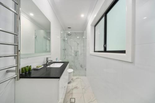 黑荒地林伍德度假屋的白色的浴室设有水槽和淋浴。