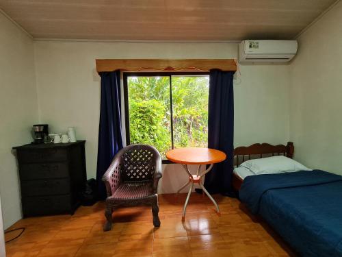 德雷克Osa Corcovado Lodge的一间卧室配有桌子、床和窗户