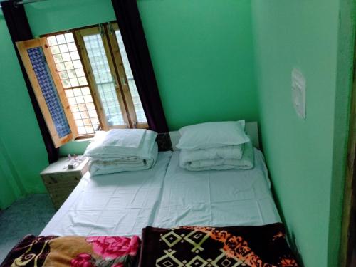 乔斯希马特Shivashram的绿色客房内的一张小床,设有两个窗户