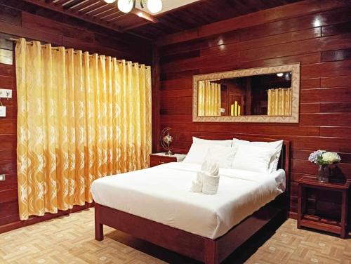 圣维森特Theresa's Pension House的卧室配有一张白色大床和木墙