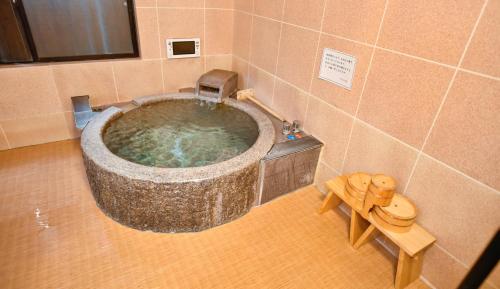 别府Kamegawa Onsen HATAGO Yuyu的客房内的浴室设有大型石头浴缸