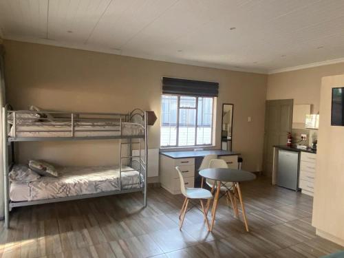 布隆方丹Aloe Guest Rooms的客房设有双层床和桌椅。