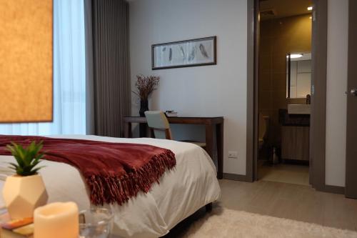 马尼拉One Uptown Residence的酒店客房配有一张床铺、一张桌子和一张书桌。