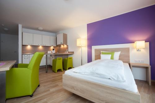 埃默里希安姆潘酒店的一间卧室配有一张床,厨房配有绿色椅子
