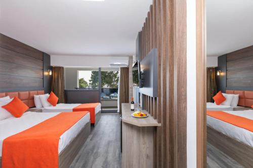 迪迪姆Maya World Didyma Hotel的酒店客房带两张带橙色床单的床