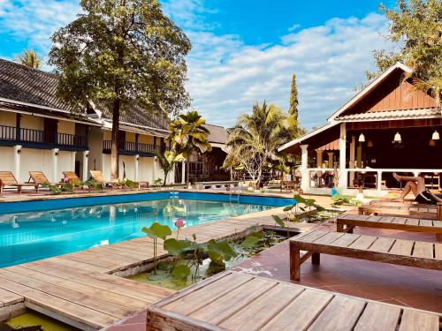 琅勃拉邦The Jam的一个带长椅和桌子的度假村游泳池