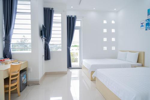 Tây NinhAn Gia Hotel Tây Ninh的一间卧室配有两张床、一张桌子和一张桌子
