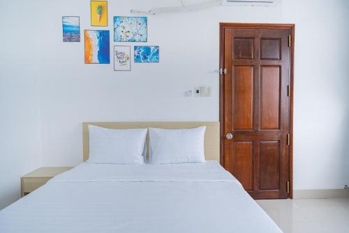 Tây NinhAn Gia Hotel Tây Ninh的卧室配有白色的床和木门