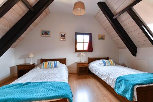 希伯维列Au Nid d'Hirondelles的配有白色墙壁和木地板的客房内的两张床