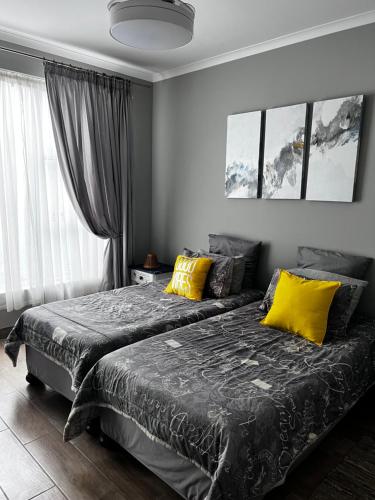 斯瓦科普蒙德5078 Swakopmund的一间卧室配有两张带黄色枕头的床