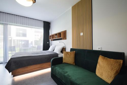 科沃布热格Apartament Royal Solny Resort z aneksem kuchennym w hotelu z krytym basenem, sauną i usługami SPA的一间卧室配有一张床和一张绿色沙发