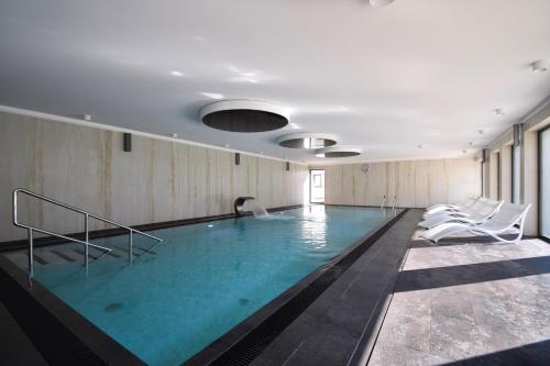 科沃布热格Apartament Royal Solny Resort z aneksem kuchennym w hotelu z krytym basenem, sauną i usługami SPA的一个带椅子的大型游泳池