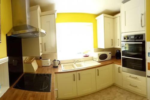 赫克瑟姆The Side - Hexham的厨房配有白色橱柜、水槽和窗户。