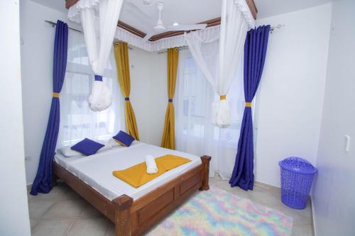 马林迪Kijani Suites的一间卧室配有蓝色和黄色窗帘的床