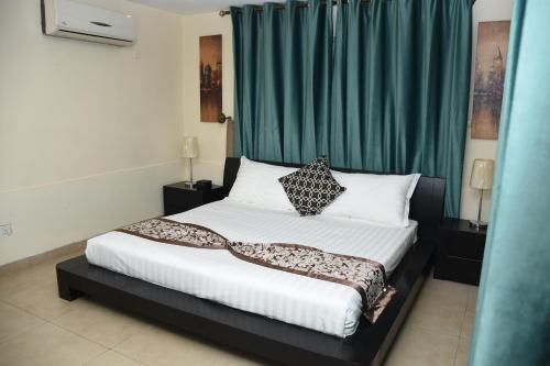安曼里亚姆公寓的一间卧室配有一张带绿帘的床