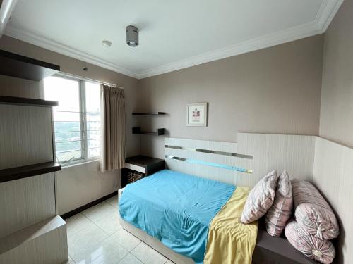 万隆Galeri Ciumbuleuit Apartment 1 2BR 1BA - code 26A的一间卧室配有一张带蓝色床单的床和一扇窗户。