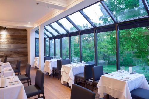 三河城圣皮埃尔湖酒店的餐厅设有桌椅和大窗户。
