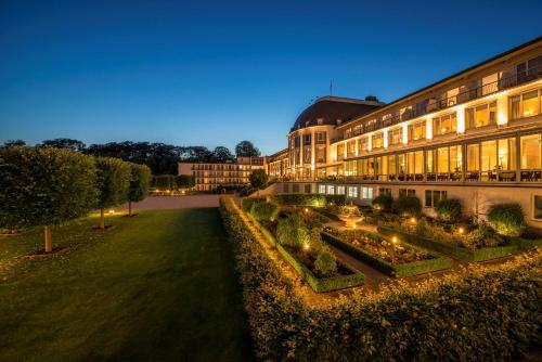 不莱梅Parkhotel Bremen – ein Mitglied der Hommage Luxury Hotels Collection的一座建筑,前方有一个花园,晚上