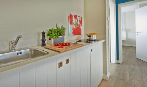 科尔斯万特Dorint Resort Baltic Hills Usedom的厨房柜台设有水槽和带西红柿的切板
