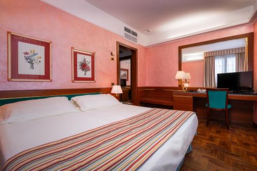 米兰克里维斯酒店的一间卧室配有一张床、一张书桌和一台电视