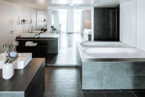 柏林柏灵Q!酒店的浴室配有两个盥洗盆和浴缸。