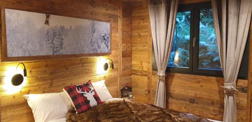 尚佩里Chalet le Grenier des Crosets的一间卧室设有木墙、一张沙发和一个窗口