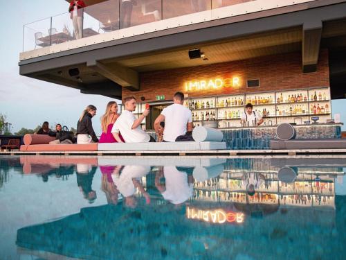 米兰21 House of Stories Navigli的一群人坐在游泳池旁的酒吧里