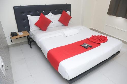 卡延Hotel Leesha Residency的一间卧室配有一张带红色枕头的大床