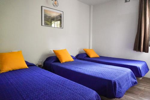 埃尔米瓜El Cedro Cottage Home的配有蓝色和橙色枕头的三张床