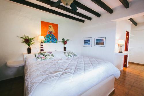 圣卡塔利娜岛OceanFront Bungalows - Paradise Rentals的卧室配有一张白色床,墙上挂有绘画作品