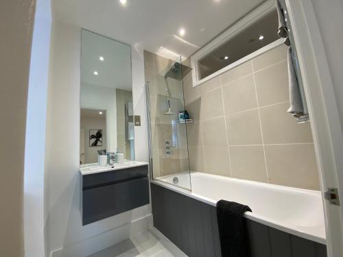 伦敦Stylish Traveller's Heaven的带浴缸、水槽和镜子的浴室