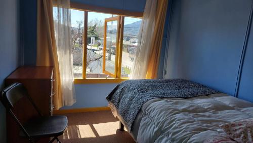 科伊艾科Pies a tierra的一间卧室设有一张床、一个窗口和一把椅子